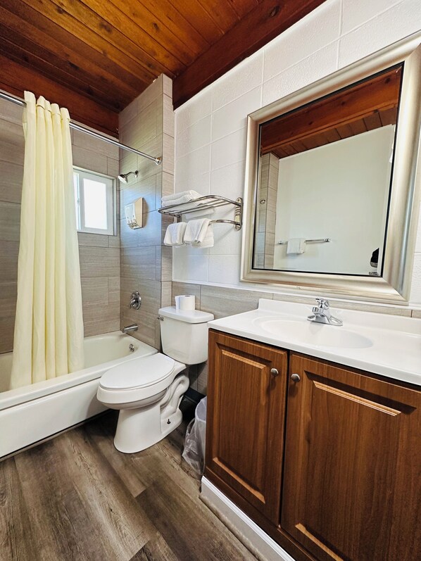 A bathroom with a bathtub, toilet, and vanity with a mirror.