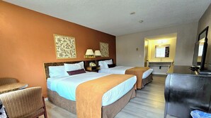 A hotel room with two beds, a desk, a chair, and a mirror. - Swiss Village Inn (Golden)