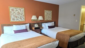 A hotel room with two beds, a nightstand with a lamp, and a telephone.