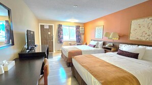 A hotel room with two beds, a desk, a chair, a TV, a phone, and a window with curtains. - Swiss Village Inn (Golden)