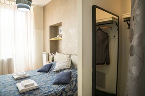 A bedroom with a bed, a mirror, a wardrobe, and a shelf with toiletries. - Il Sesto Suites Central (Rome)