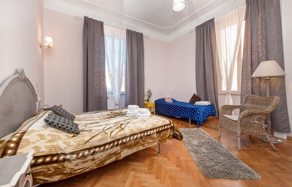 A hotel room with a bed, a chair, a small table, and a lamp. - Il Sesto Suites Central (Rome)