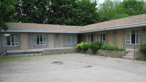 A motel with a gravel parking area and a small garden. - Clarkson Village Motel (Mississauga)
