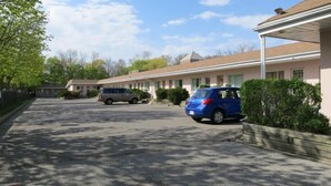 A row of single-story motel buildings with a parking lot in front. - Clarkson Village Motel (Mississauga)