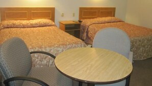 A hotel room with two beds, a small table, and two chairs. - Clarkson Village Motel (Mississauga)