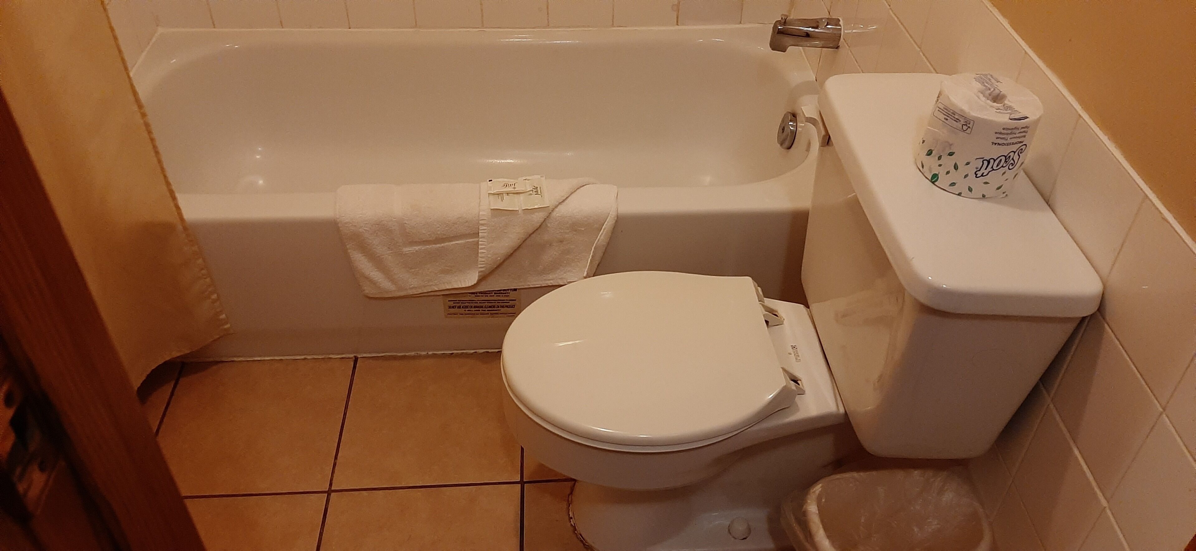 Een badkamer met een bad, toilet en een rol toiletpapier.