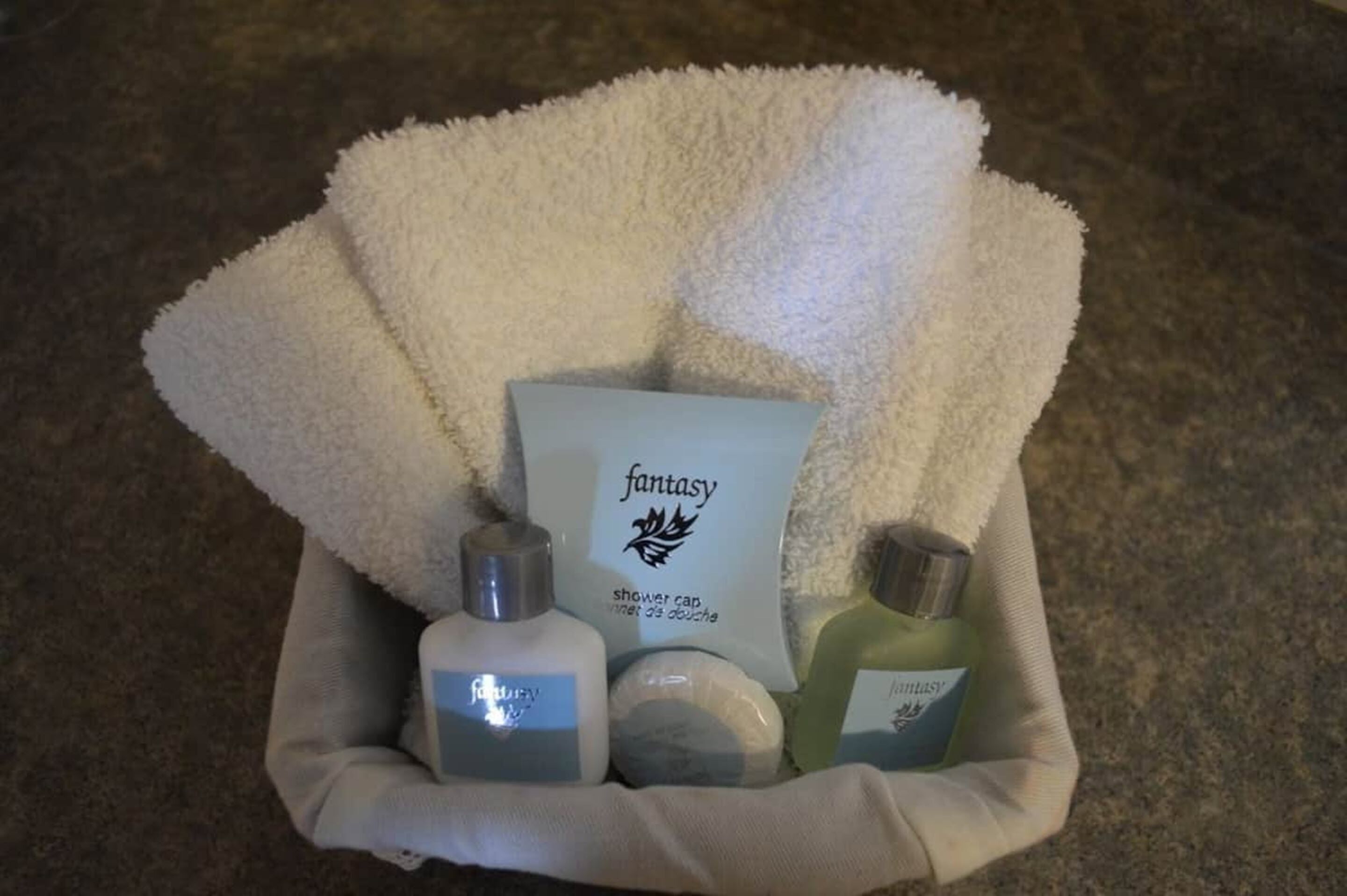 A bathroom sink area with a white towel, a shower cap, and two bottles of liquid soap.