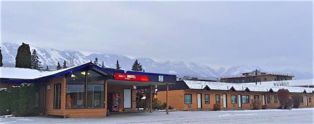 Een motel met een overdekte ingang en een uitzicht op besneeuwde bergen op de achtergrond.