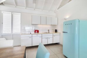 A modern kitchen with white cabinets, a light blue refrigerator, and a red toaster.
