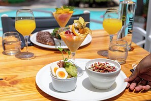 A dining table with a variety of dishes, including a bowl of salad, a bowl of grains, and a dessert in a glass. There are also two glasses of orange juice and a bottle of water.