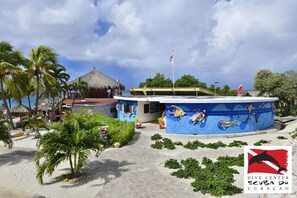 A dive center with a mural of divers, palm trees, and a thatched-roof building.
