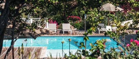 A pool area with lounge chairs and a wooden deck.