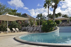 Ein Poolbereich mit Liegestühlen, Sonnenschirmen und Palmen.