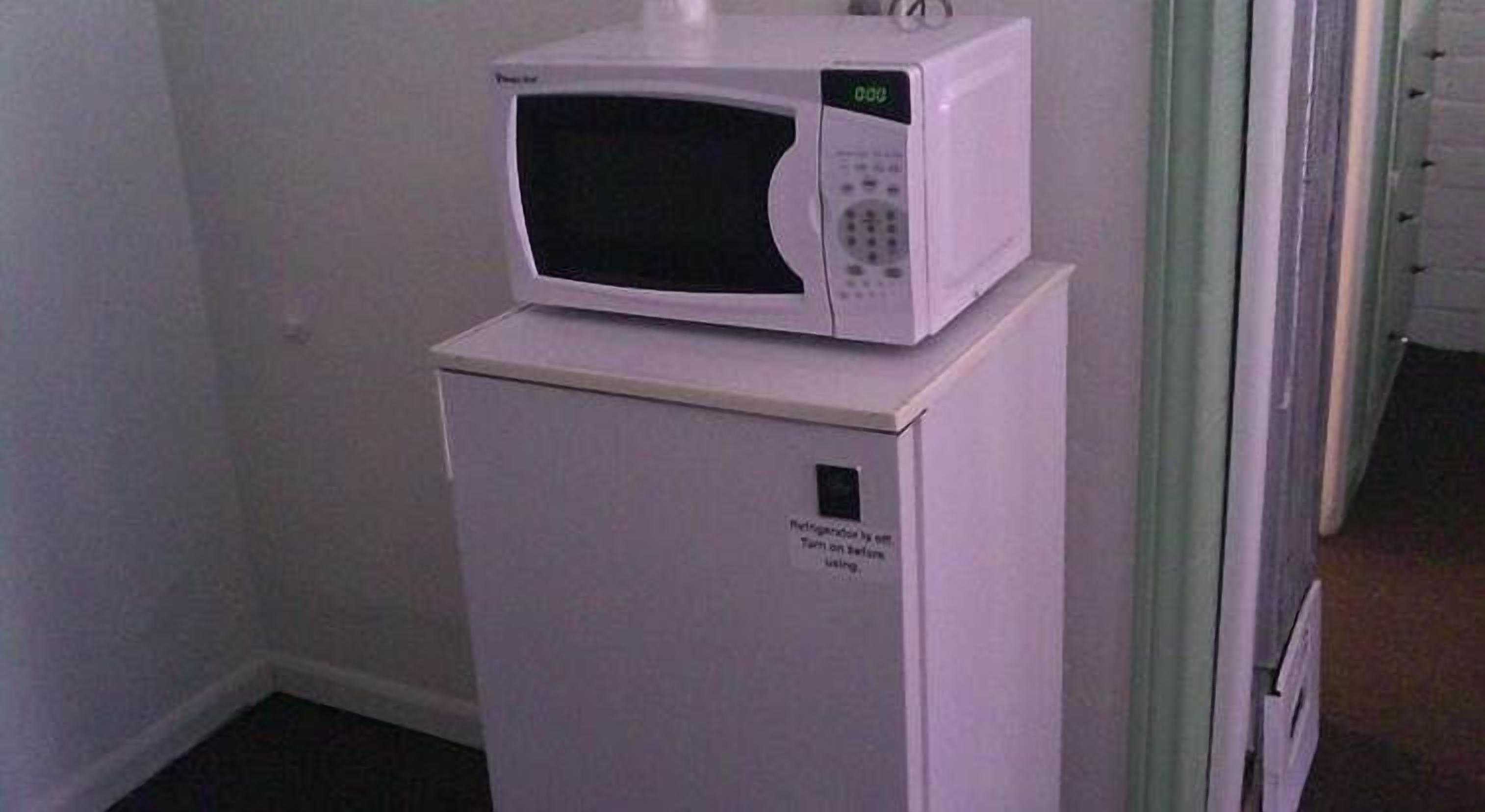A white refrigerator with a microwave on top.