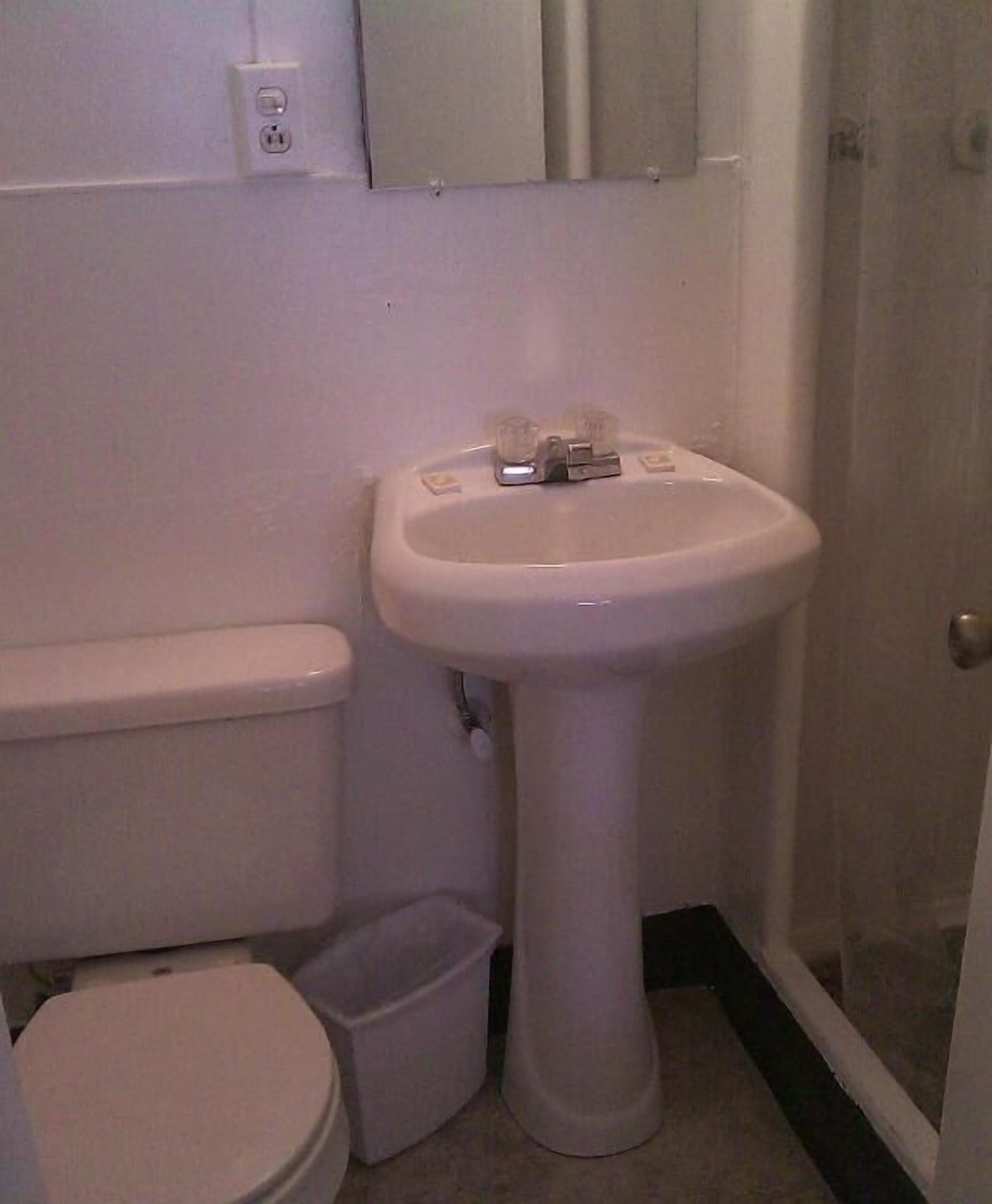 Ein kleines Badezimmer mit Toilette, Waschtisch und Mülleimer.