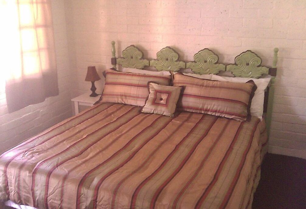 A bed with a striped bedspread, a headboard with decorative elements, and a nightstand with a lamp.