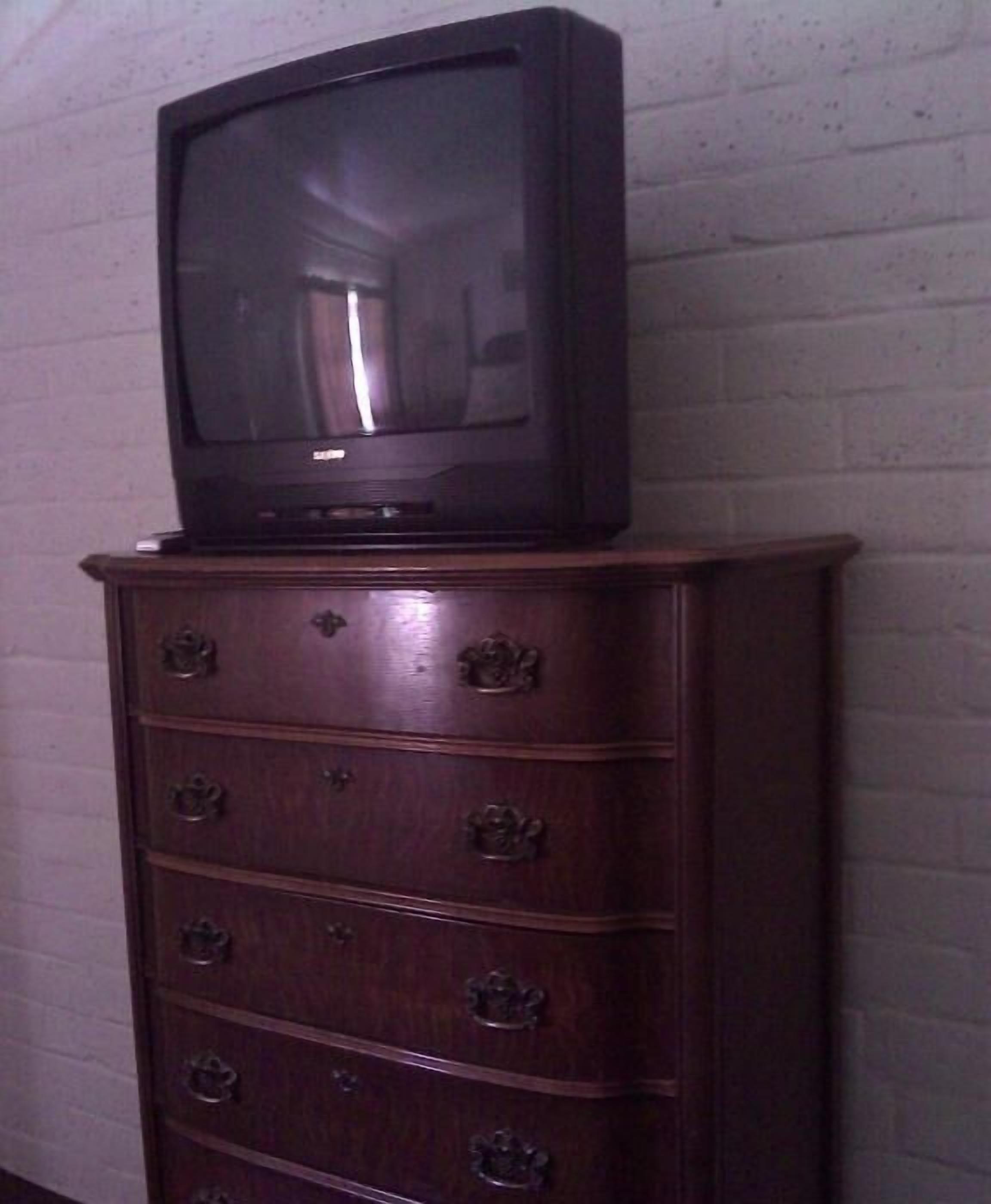 Eine Holzkommode mit einem Fernseher darauf.