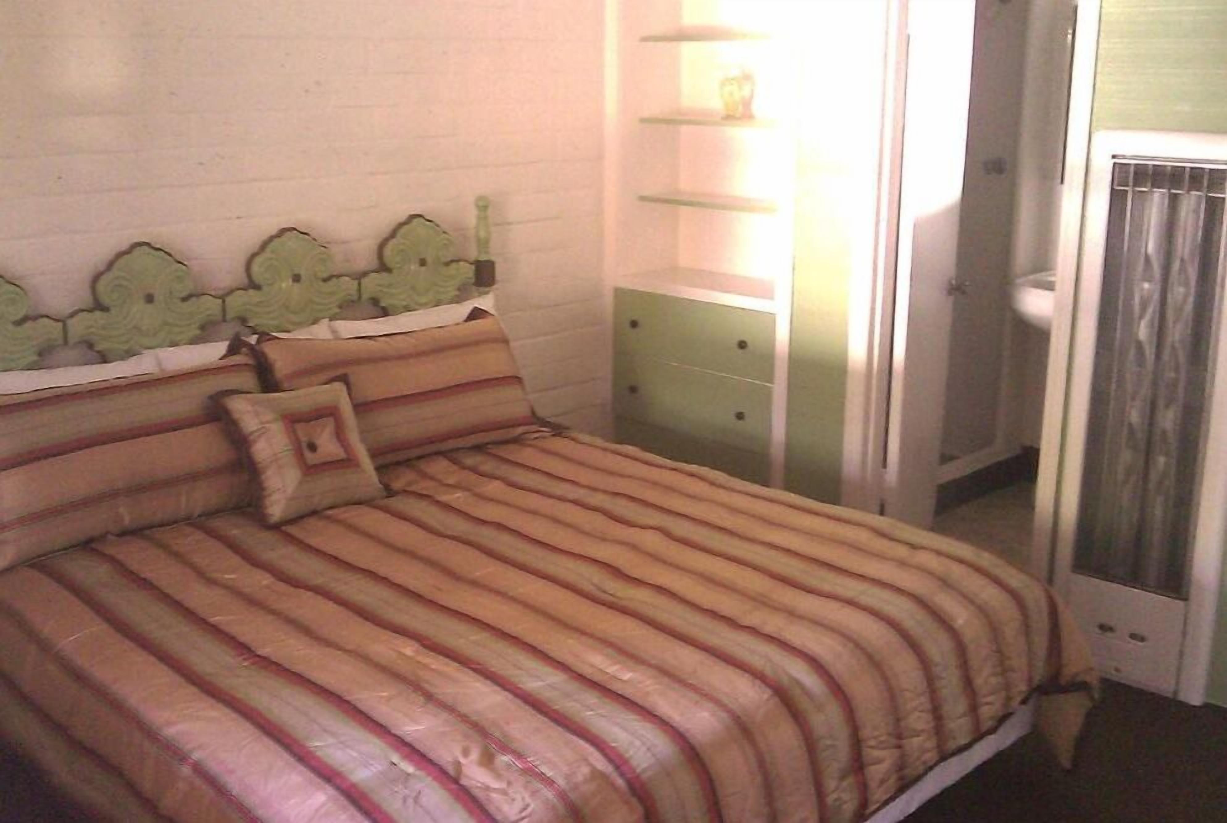 A bed with striped bedding, a bedside table, and a shelf with decorative items.