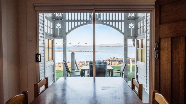 Comedor con vista al mar a través de una pérgola de madera.