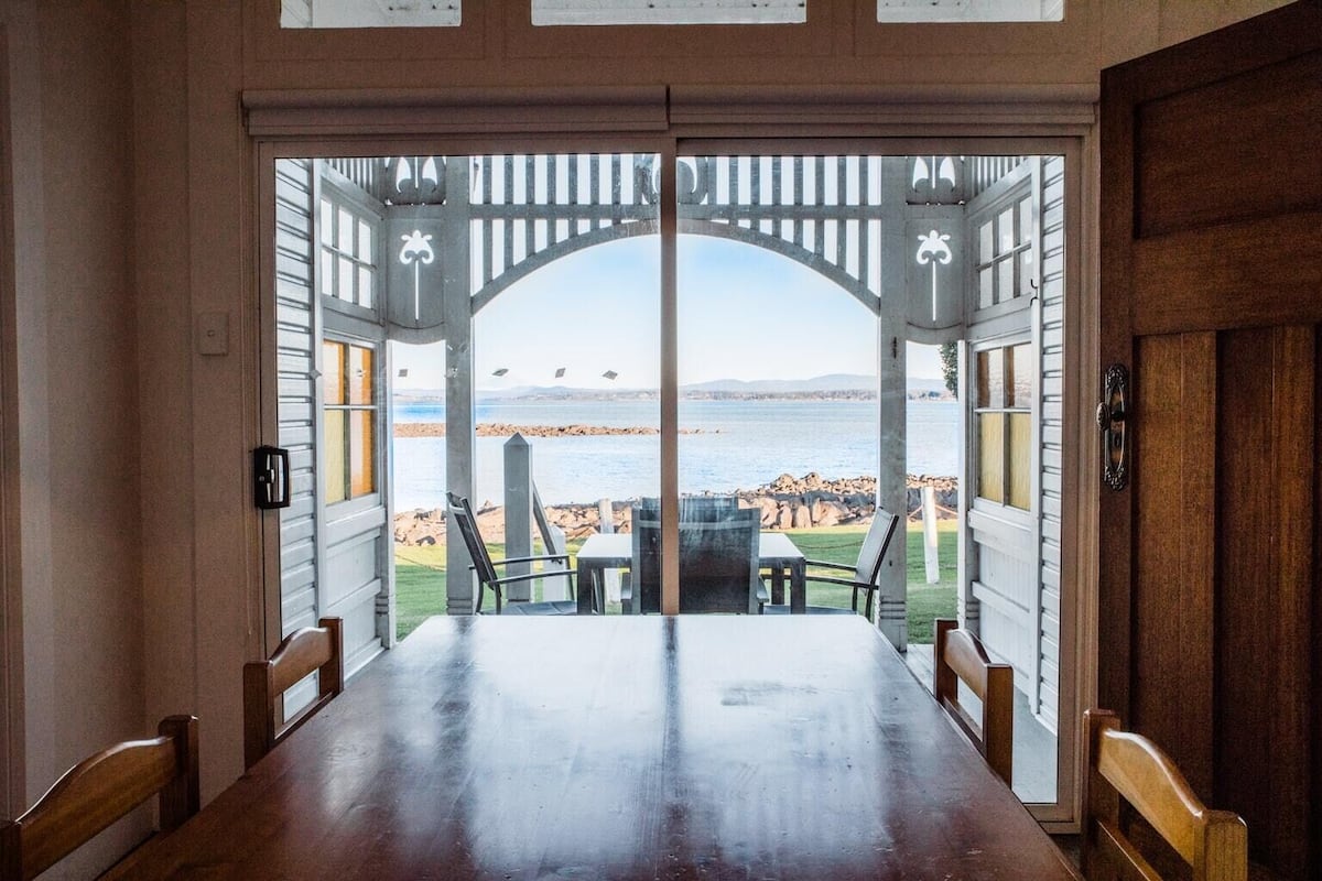 Comedor con vista al mar a través de una pérgola de madera.