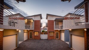 A modern building with two-story balconies, a central entrance, and garage doors.