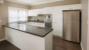 A modern kitchen with white cabinets, a stainless steel refrigerator, and a large island with a dark countertop.