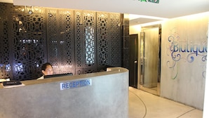 A reception area with a 'RECEPTION' sign, a decorative panel, and a door labeled 'Blutique'. - Blutique Hotel (Bangkok)