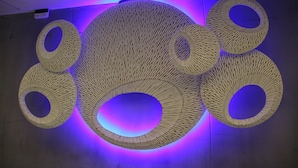 A large, circular wooden structure with multiple openings, illuminated by blue and purple lighting. - Blutique Hotel (Bangkok)