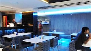 A modern restaurant with high tables and cushioned seating. - Blutique Hotel (Bangkok)