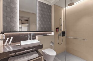Un baño moderno con un espejo grande, un lavamanos blanco, un inodoro y una zona de ducha.