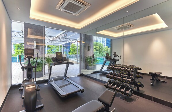 A modern gym with cardio equipment, dumbbells, and a treadmill.