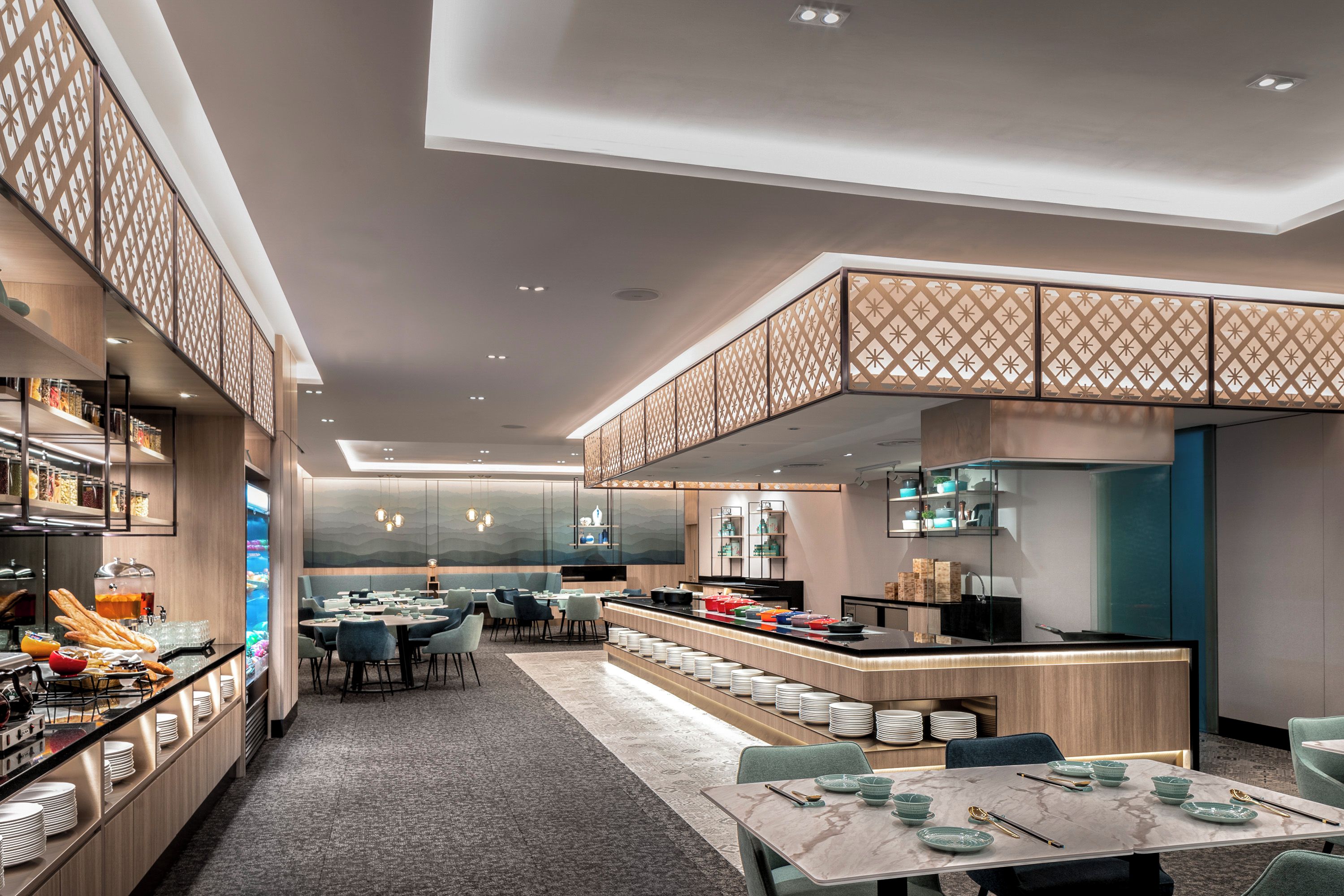 Un restaurant moderne doté d’un long comptoir, de plusieurs tables et d’un plafond décoratif.