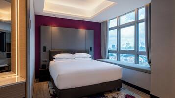 A modern hotel room with a large bed, a city view, and a walk-in closet.