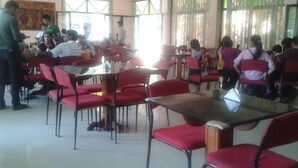 A cafeteria with red chairs and tables, large windows, and a painting on the wall. - Old Goa Residency (Panaji)