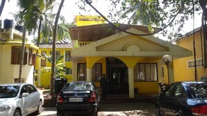 A yellow building with a covered entrance and parked cars. - Old Goa Residency (Panaji)