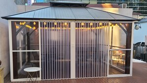 A covered outdoor seating area with a glass partition, a table, and chairs. - Le Mong Hotel (Seoul)