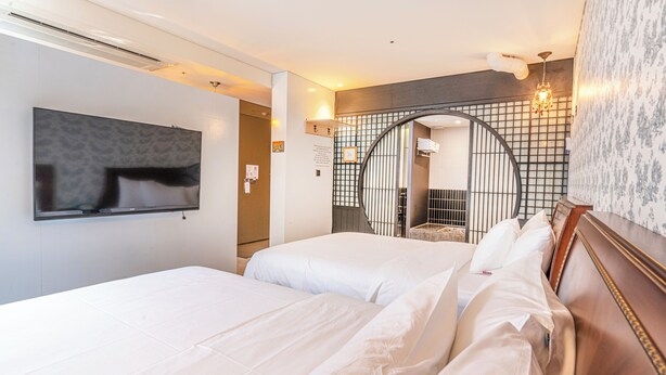 A hotel room with two beds, a TV mounted on the wall, and a decorative archway with a mirror. - Le Mong Hotel (Seoul)
