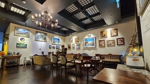 A cozy interior with wooden furniture, a chandelier, and artwork on the walls. - Le Mong Hotel (Seoul)
