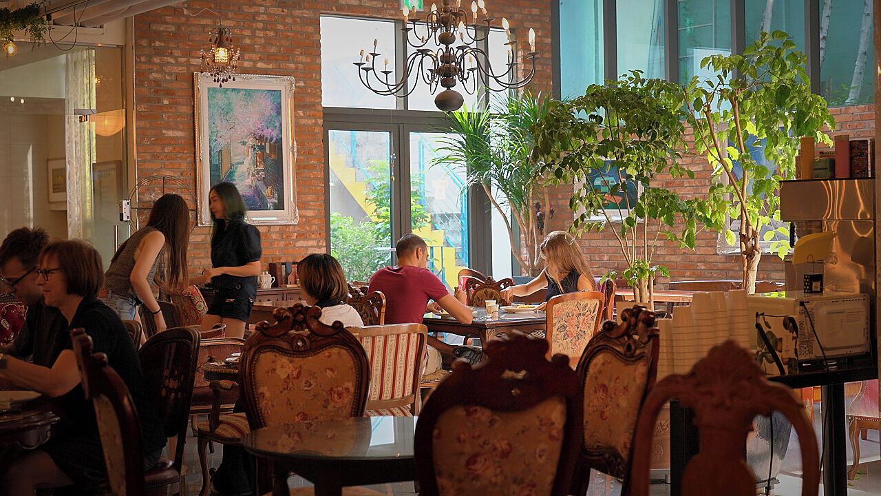 A restaurant with brick walls, large windows, and wooden furniture.