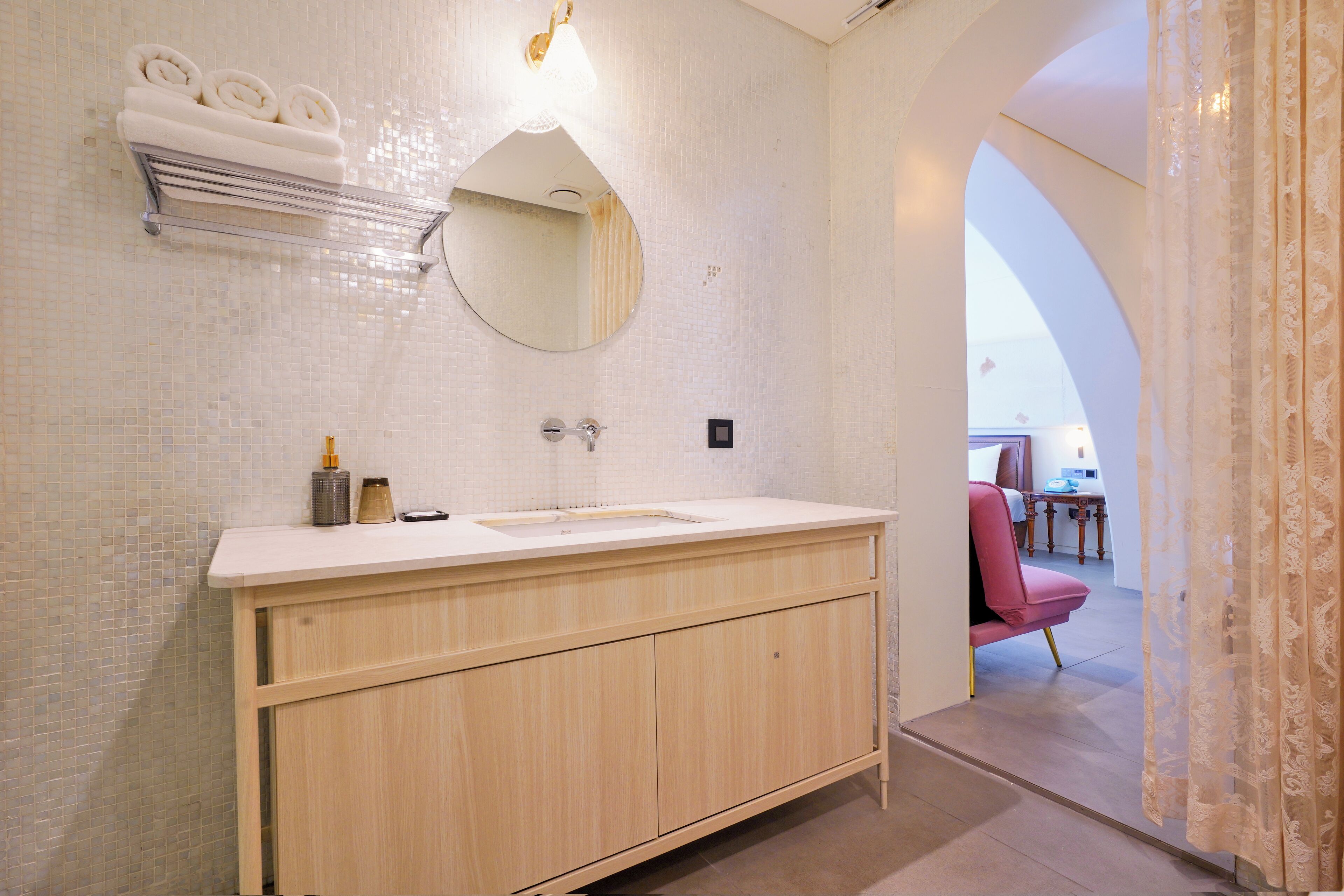 A modern bathroom with a wooden vanity, a round mirror, and a towel rack.