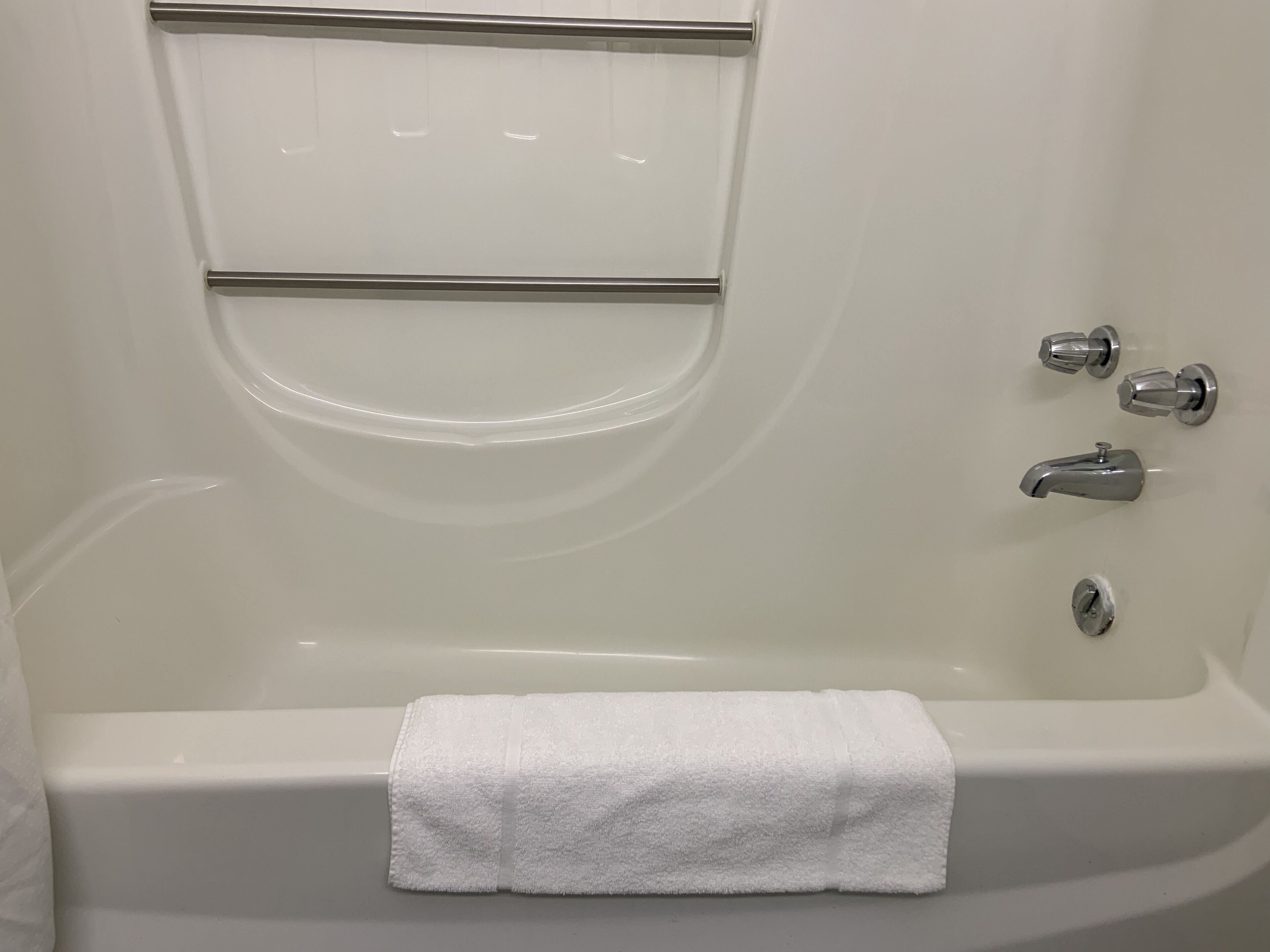 Eine weiße Badewanne mit Handtuch, chromfarbenen Armaturen und Bedienfeld.