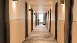 Un largo pasillo con paneles de madera, iluminación empotrada y alfombra estampada.
