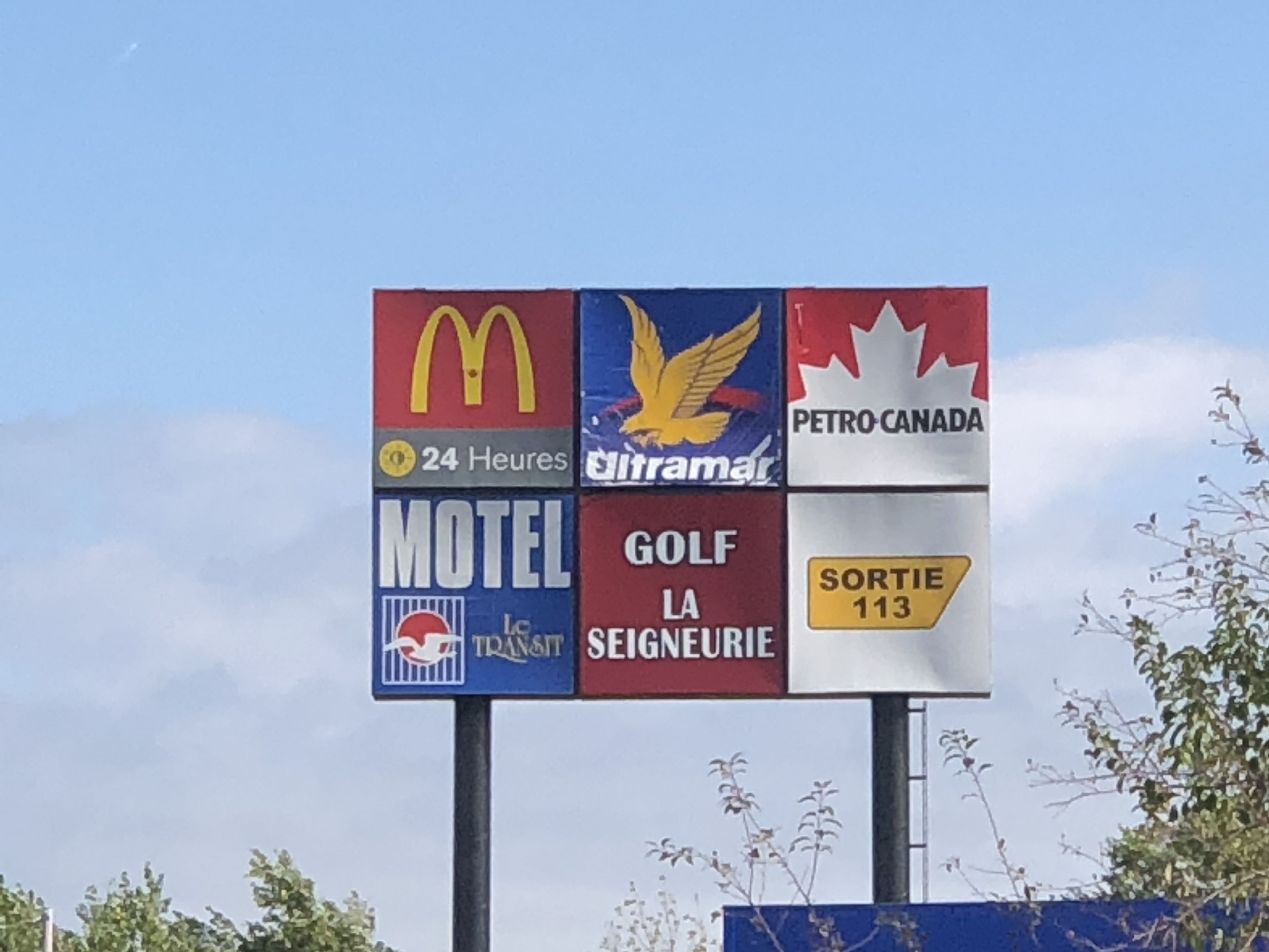 A sign with logos of McDonald's, Transat, and a motel.
