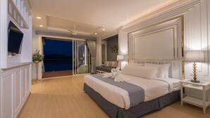 Um quarto espaçoso com uma cama grande, televisão montada na parede, varanda com vista e ventilador de teto.