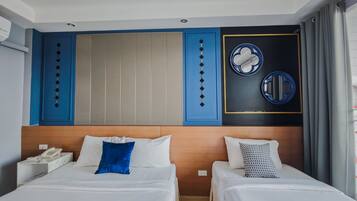 Une chambre d’hôtel avec deux lits, une tête de lit en bois, un téléphone fixé au mur et un miroir décoratif.