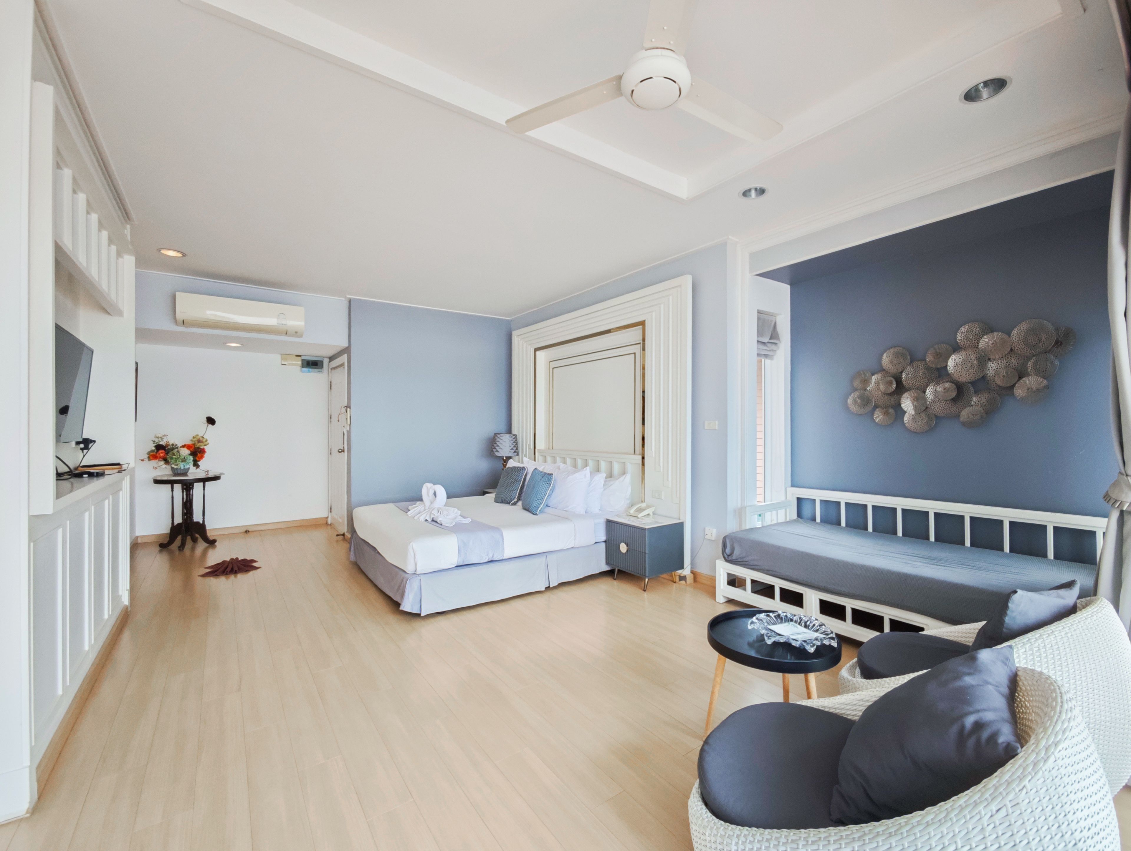 A modern hotel room with a bed, seating area, and a dining table.