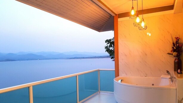 Uma casa de banho moderna com uma banheira grande, varanda envidraçada e vista para a água.
