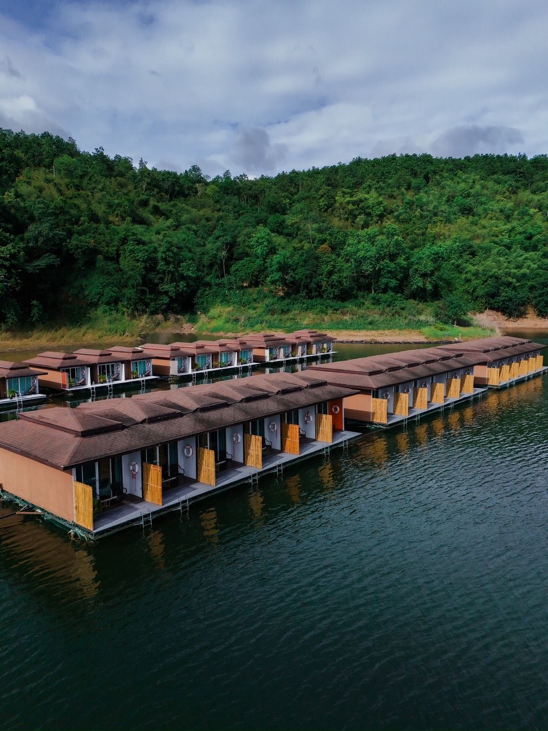 Bungalows flottants offrant une vue sur une colline boisée.