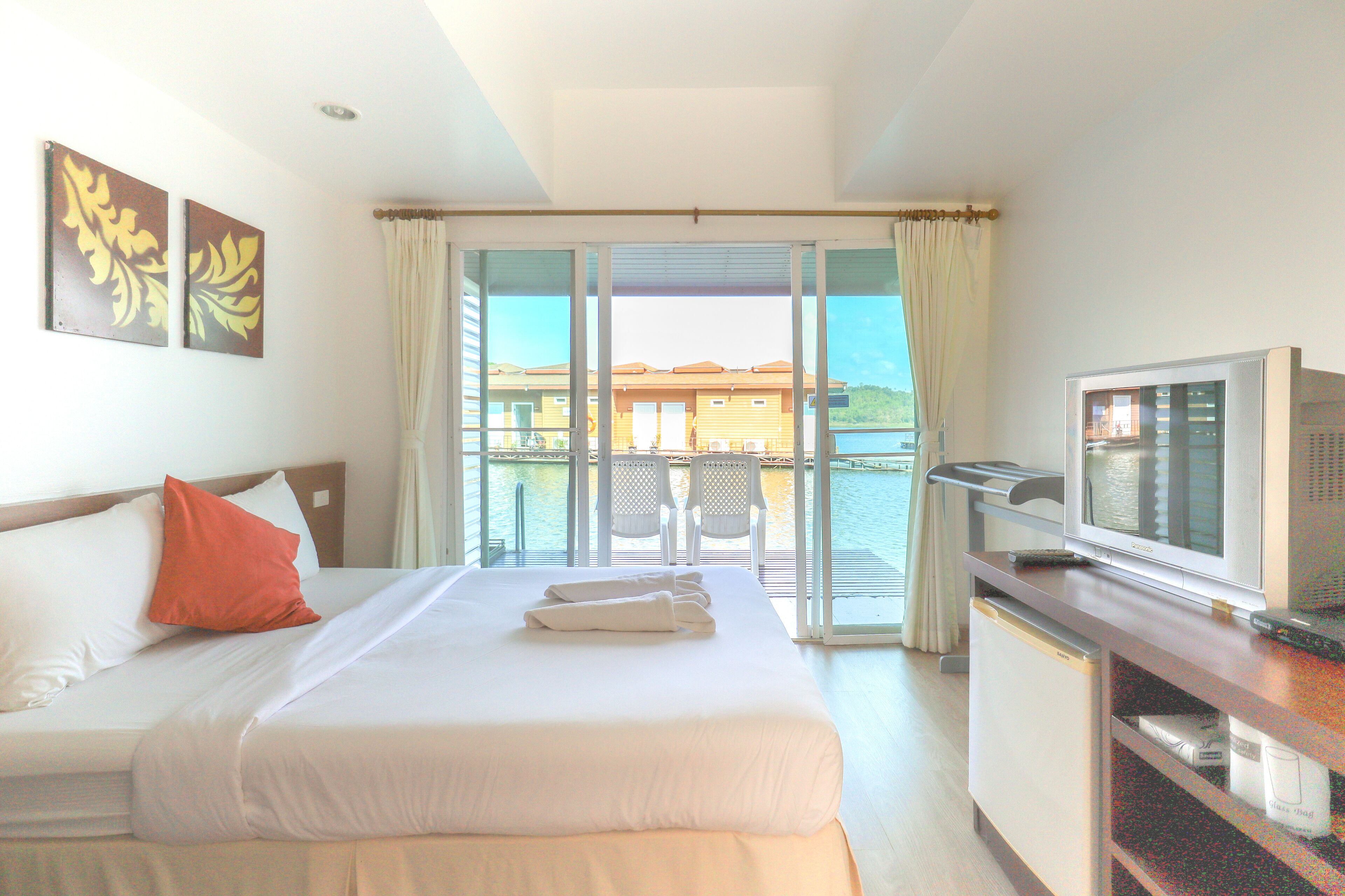 Habitación de hotel con cama, televisión y vista al mar.