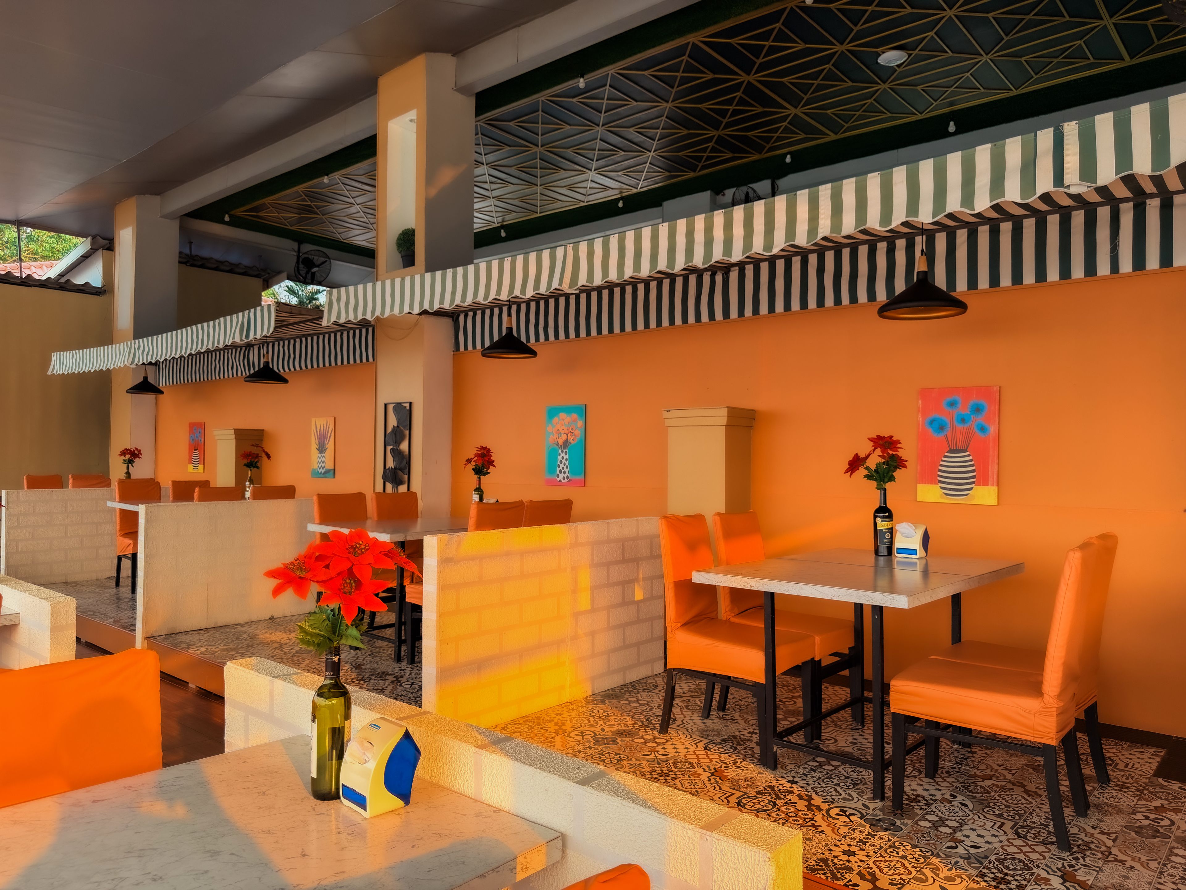 A restaurant with outdoor seating, tables, chairs, and decorative wall art.